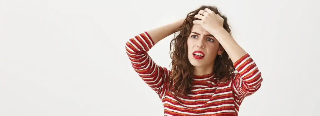 Mujer joven tocándose la cabeza para intentar aliviar su burnout laboral.