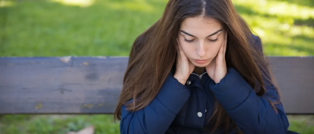 Mujer sentada en el parque después de combinar alcohol y medicamentos. 