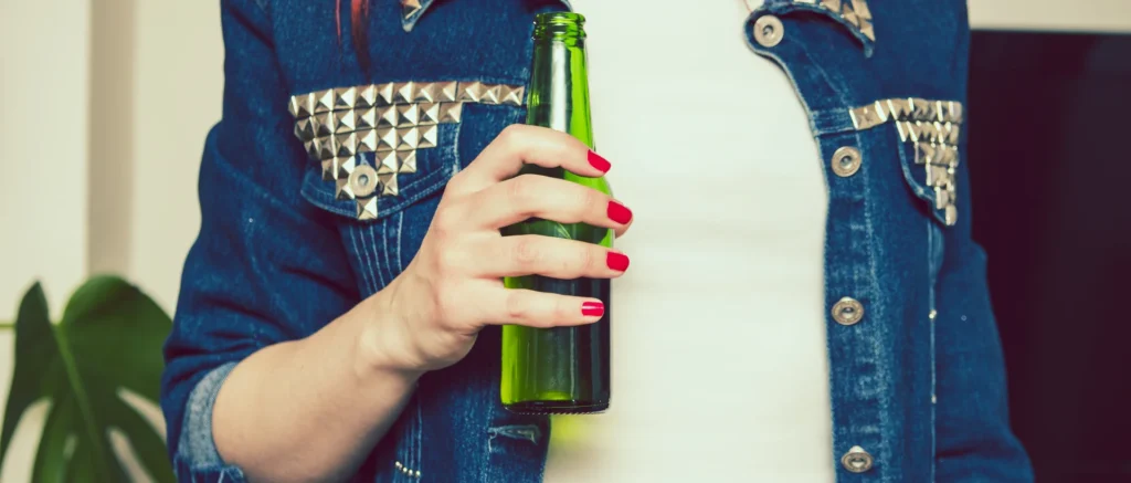 Mujer con una botella de bebida alcohólica en su mano.